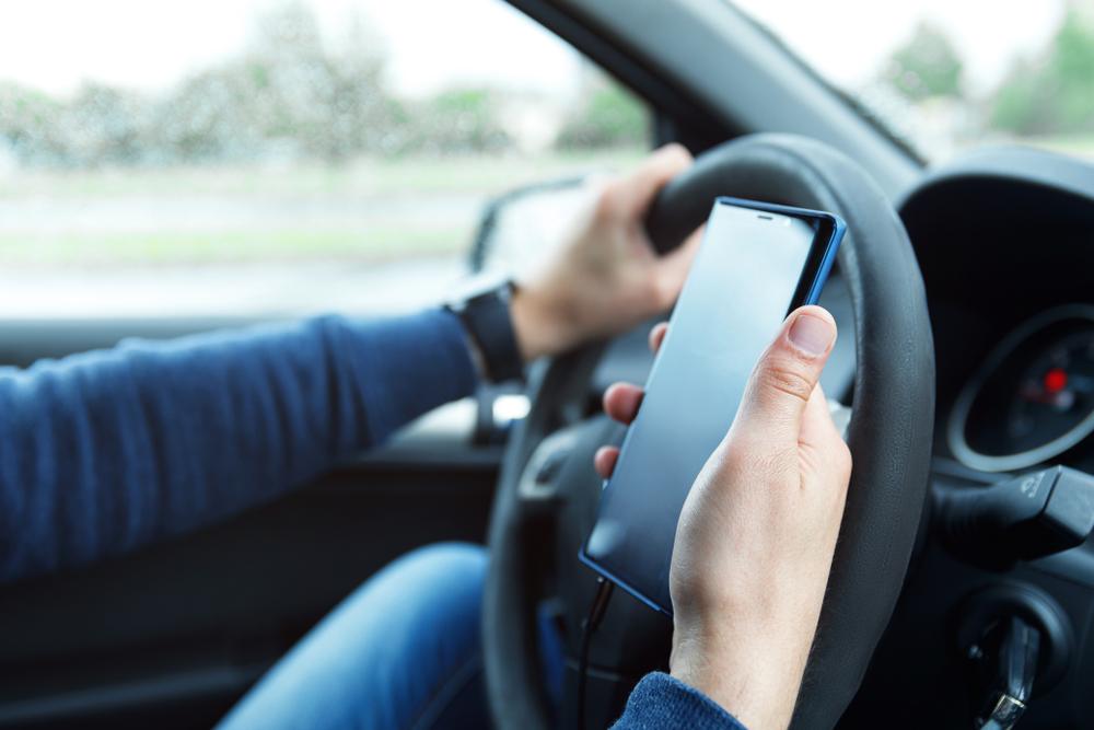 A rideshare driver checks a cell phone for incoming ride requests as he wonders about how common rideshare accidents are.