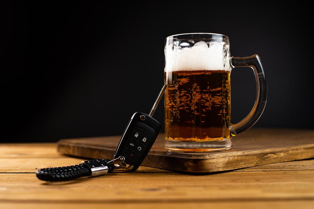 car key and beer on a wooden table