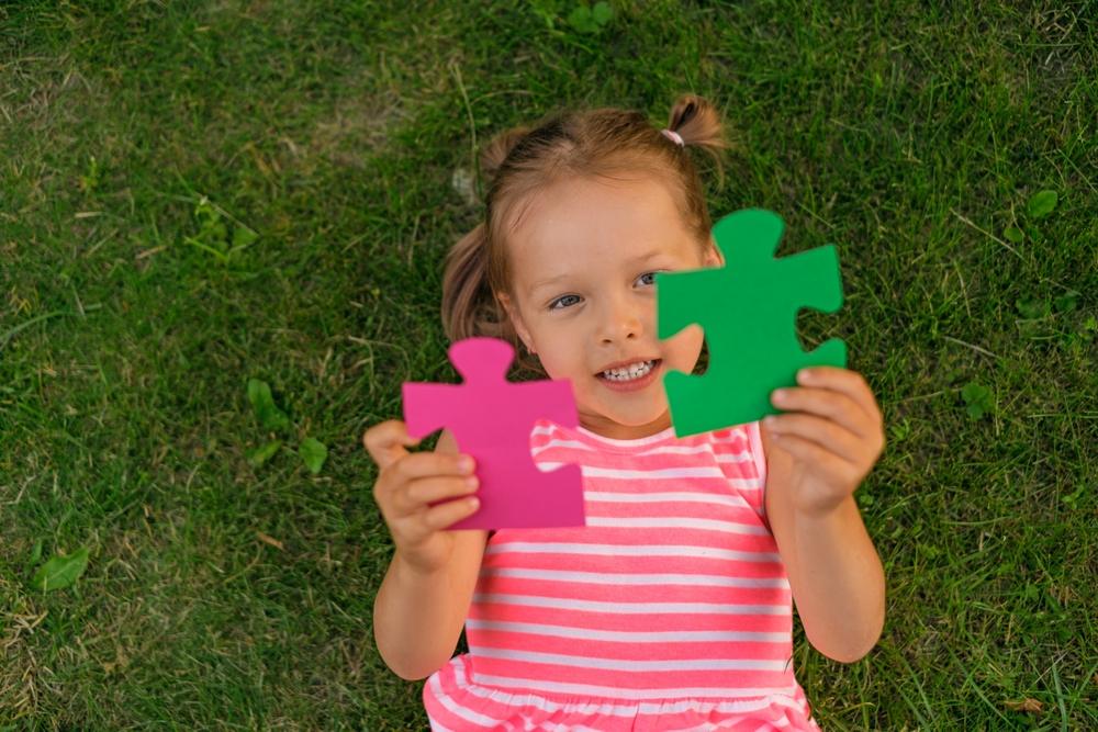 child holds two large pieces in the shape of a puzzle lying