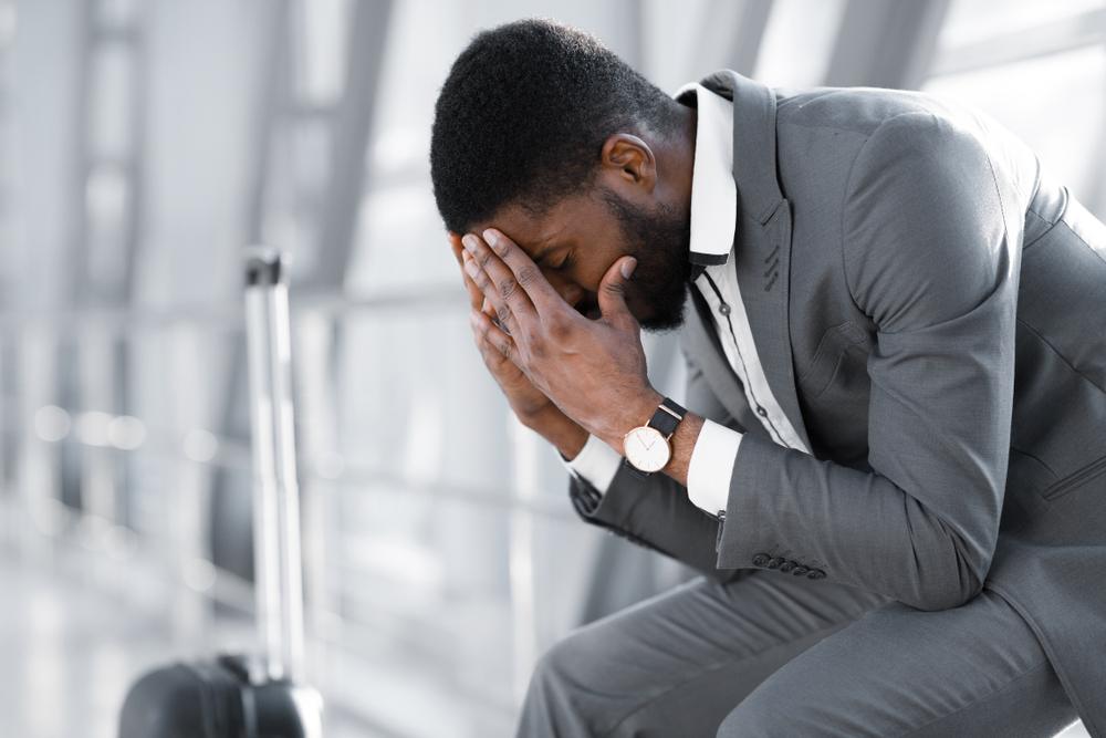 depressed man sitting at airport with baggage