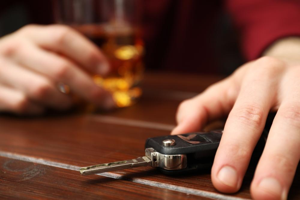 Drunk man reaching for car keys at table