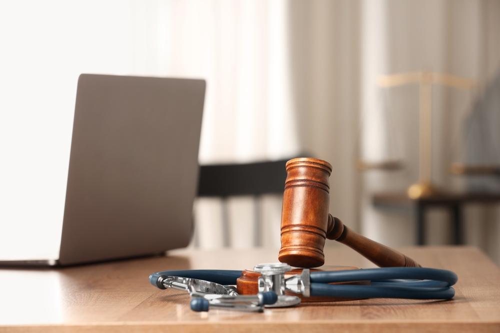 gavel laptop and stethoscope on wooden table