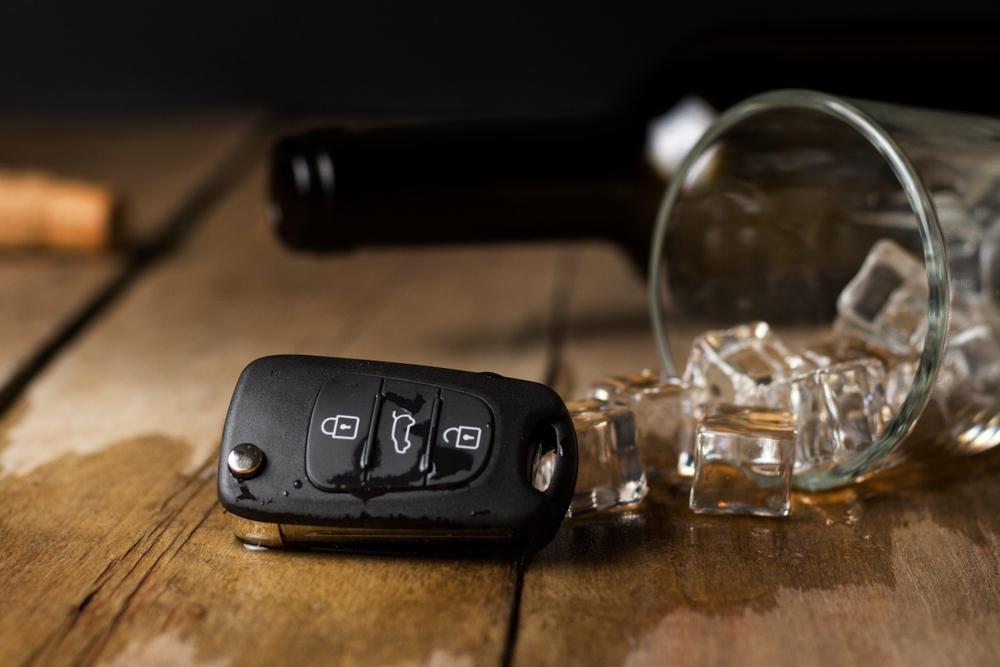glass with spilled alcoholic beverage and car keys