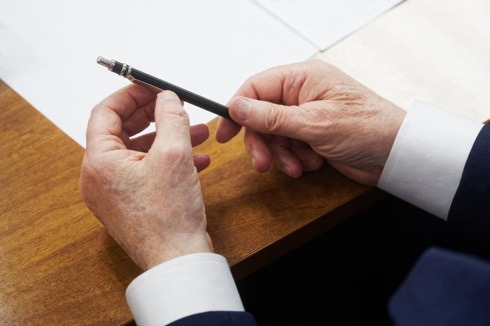 hands of an elderly man holding a pen