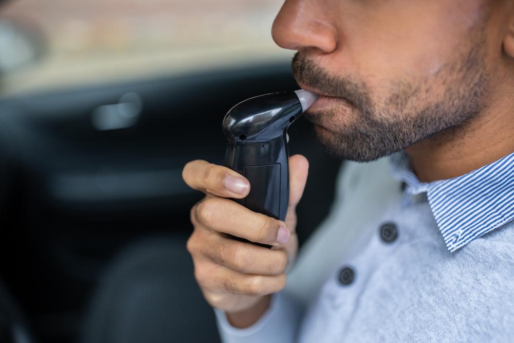 man sitting inside car taking alcohol test
