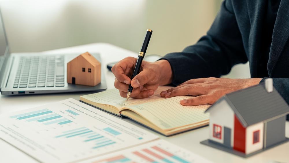 Real estate agent uses calculator to calculate cost of home