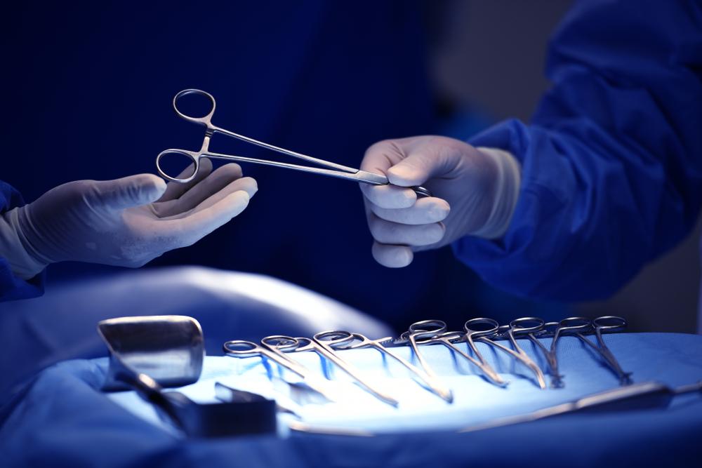 Surgeon hand picking up an instrument from tray