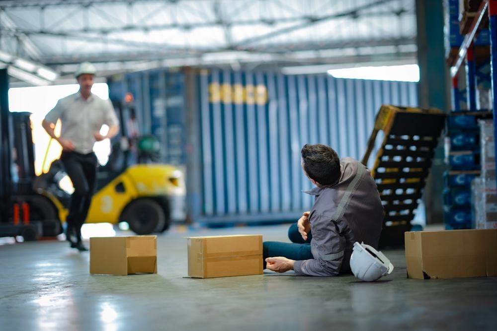 worker lies on ground after fall in warehouse